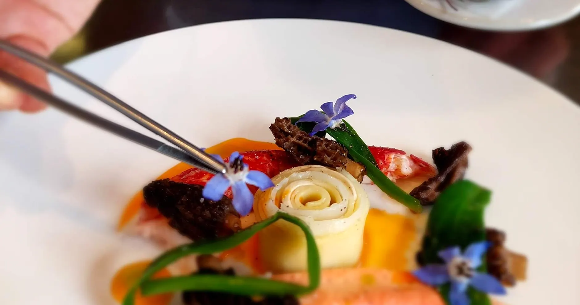 De chef werkt een bord af met een pincet